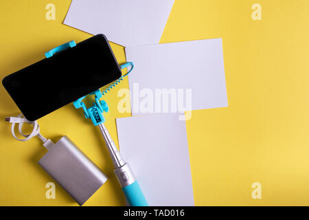 Mise à plat avec un monopode et smartphone photos sur un fond jaune. Concept voyages d'été. Banque D'Images