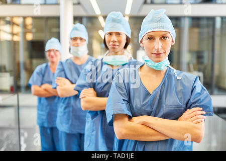 Jeune chirurgien avec bras croisés en face de sa chirurgie et équipe d'urgence. Banque D'Images