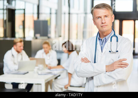 L'homme en tant que médecin en chef à l'autorité et de la confiance en soi en face de sa clinique de l'équipe de médecins Banque D'Images