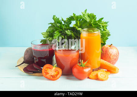 Jus de fruits frais smoothies à partir d'une variété de betterave Légumes Tomates Carottes apple dans les verres en bois sur fond bleu. Banque D'Images