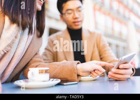 Espagne, Madrid, jeune couple à l'aide de téléphone cellulaire dans un café sur la Plaza Mayor Banque D'Images