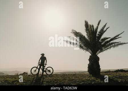 L'Espagne, Lanzarote, mountainbiker lors d'un voyage près de palm tree Banque D'Images