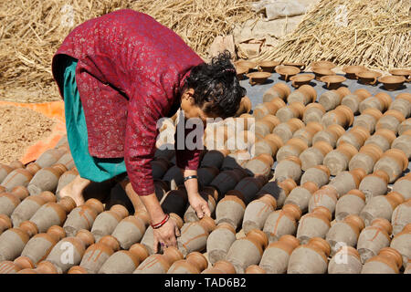 Femme tournant des pots d'argile qu'ils sun-sec en Kumale Tol (Potters' Square, Place Pottery), Bhaktapur, Vallée de Katmandou, Népal Banque D'Images