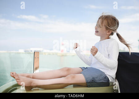 Heureux petite fille assise sur une chaise longue work Banque D'Images