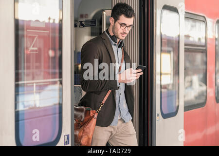 Young man using cell phone in commuter train Banque D'Images