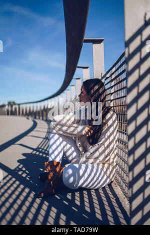 Jeune femme assise sur un pont Banque D'Images