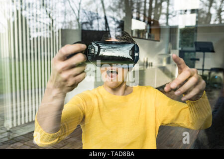 Portrait de femme étonné derrière la vitre à l'aide de lunettes de réalité virtuelle Banque D'Images