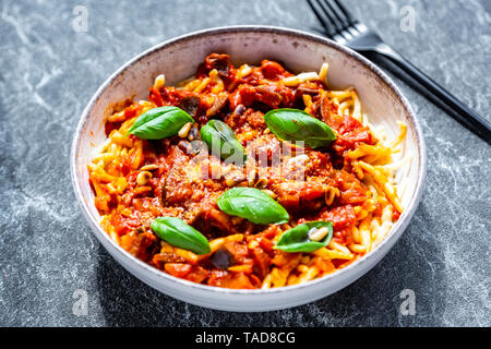 Bol de pâtes aux tomates aubergine sugo garnie avec les pignons de pin, parmesan et basilic Banque D'Images