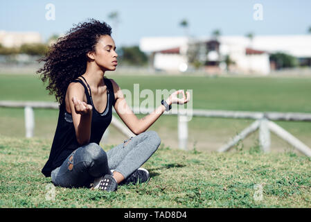 Sporty young woman doing yoga on lawn Banque D'Images