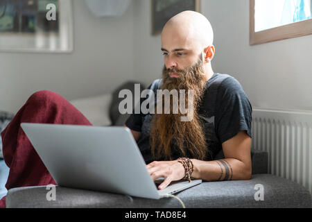 Portrait de hipster using laptop at home Banque D'Images