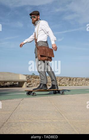 Homme barbu avec sac en cuir sur longboard Banque D'Images