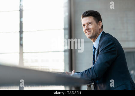 Smiling businessman leaning on railing Banque D'Images