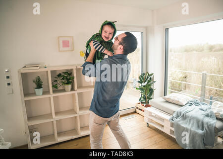 Père jouant avec son fils heureux dans un costume à la maison Banque D'Images