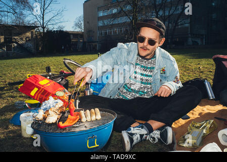 Young man having a barbecue in park Banque D'Images