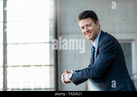 Portrait of smiling businessman leaning on railing Banque D'Images