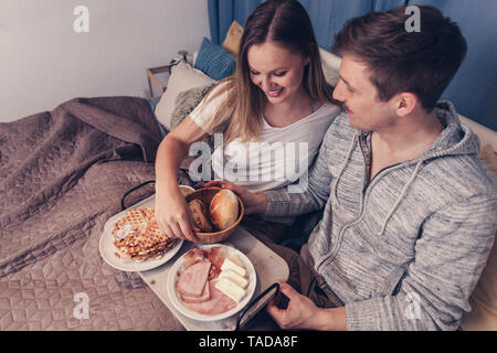 Young couple having breakfast in bed Banque D'Images