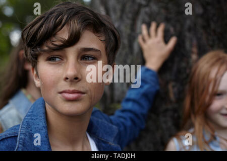 Portrait de jeune garçon avec des amis à un arbre Banque D'Images
