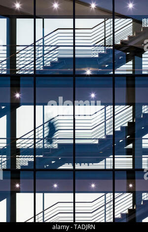 Une personne à monter un escalier dans un immeuble de bureaux Banque D'Images