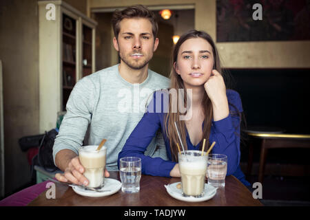 Portrait de jeune couple dans un café avec mousse de lait sur les lèvres Banque D'Images