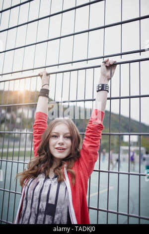 Portrait of a Teenage girl à une clôture à un terrain de sport Banque D'Images