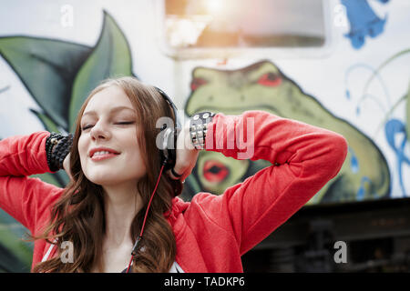 Portrait of teenage girl portant des écouteurs à un train voiture peinte Banque D'Images