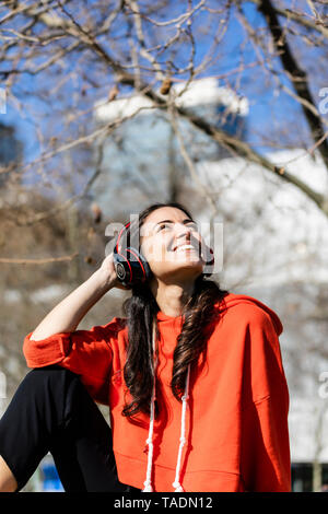 Jeune danseur contemporain porter du rouge sweat-shirt, assis et écouter de la musique Banque D'Images