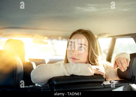 Jeune femme assise sur le siège arrière en voiture à côté Banque D'Images