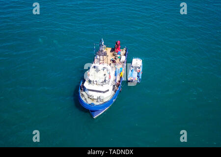 Bateau de pêche en mer avec un plus petit bateau amarré à côté - Vue aérienne de l'image. Banque D'Images