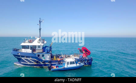 Bateau de pêche en mer avec un plus petit bateau amarré à côté - Vue aérienne de l'image. Banque D'Images