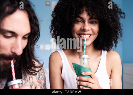 Portrait of smiling young woman with boyfriend smoothie potable Banque D'Images