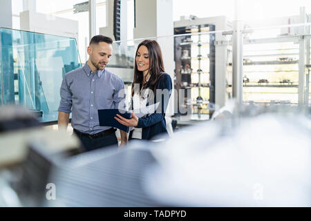 Smiling businessman and businesswoman looking at dossier dans l'usine moderne Banque D'Images