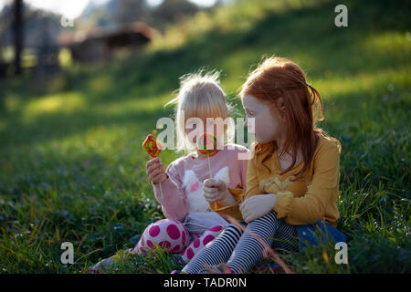 Deux soeurs assis dans un champ holding lollipops Banque D'Images