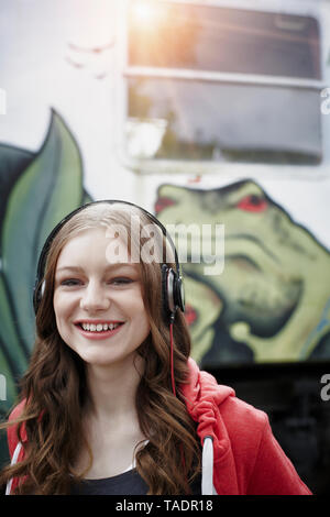 Portrait of teenage girl wearing écouteurs à un train voiture peinte Banque D'Images