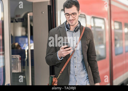 Young man using cell phone at commuter train Banque D'Images