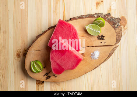 Steak de thon cru frais sur la planche à découper en bois, vue du dessus. Banque D'Images