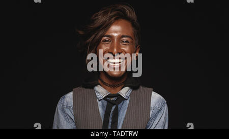 Homme à la mode isolé sur fond noir et de rire. Close up of young indian man looking at camera et rire. Banque D'Images