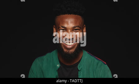 Portrait of a happy african man looking at camera et souriant. African Male avec barbe isolé sur fond noir et de rire. Banque D'Images
