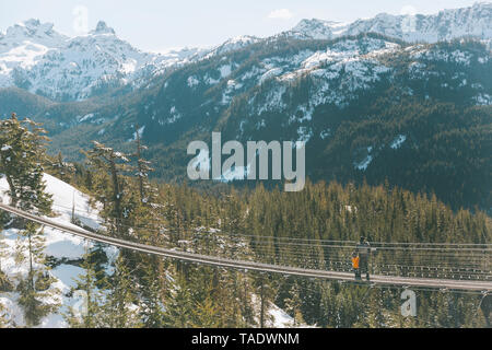 Père et fils marchant sur un pont suspendu dans les montagnes, Squamish, Canada Banque D'Images
