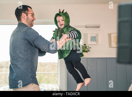 Père jouant avec son fils heureux dans un costume à la maison Banque D'Images