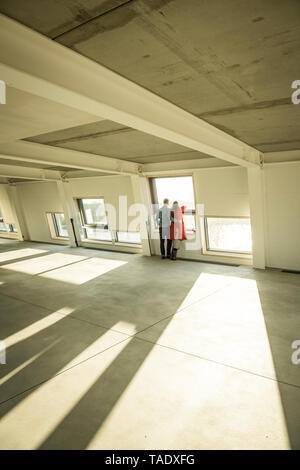 Couple à la fenêtre de sortie de leur nouvelle maison Banque D'Images