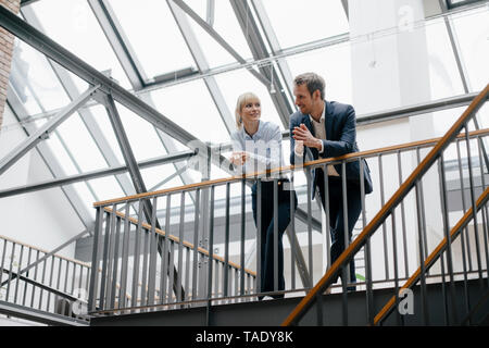 Man and Woman standing in office building, discuter Banque D'Images