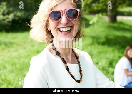 Portrait of senior woman wearing sunglasses in park Banque D'Images