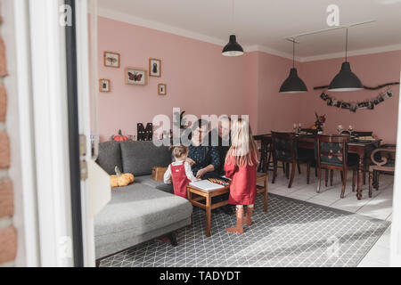 Deux jeunes filles jouant avec des grands-parents dans la salle de séjour à la maison Banque D'Images