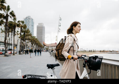 Femme avec e-bike pour avoir une pause sur le promenade de bord de plage Banque D'Images