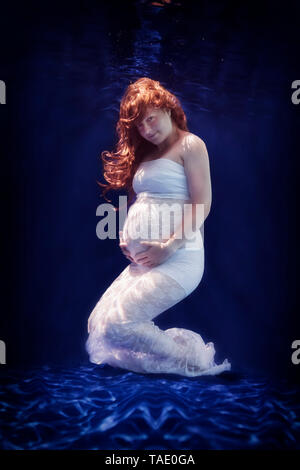 Pregnant woman wearing white dress sous l'eau Banque D'Images