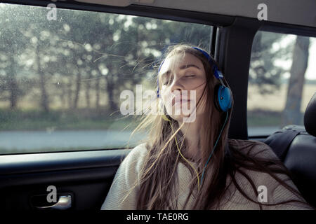 Jeune femme avec des cheveux dans une voiture portant des écouteurs Banque D'Images