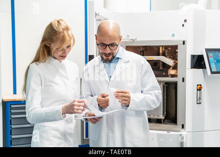 Deux techniciens de porter des blouses de laboratoire plan discussion Banque D'Images