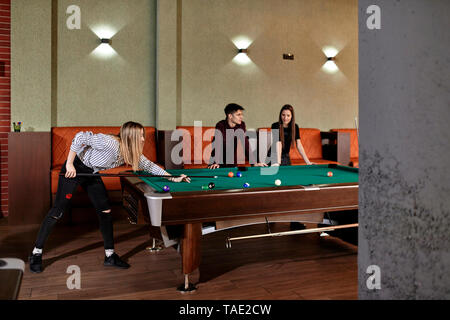 Jeune femme jouant au billard avec des amis Banque D'Images