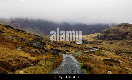 Paysage magnifique avec un ciel brumeux, la fonte des glaces et de la route entre les belles montagnes escarpées - capturés au cours d'une randonnée à Snowdon en hiver. Banque D'Images