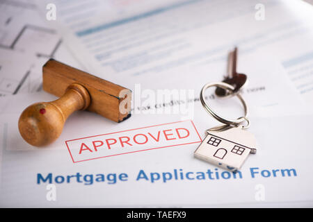 Un formulaire de demande de prêt hypothécaire approuvé avec clé de la maison et tampon de caoutchouc close up Banque D'Images